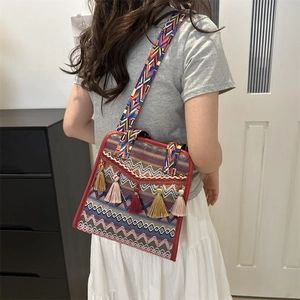Detail of bohemian shoulder bag with vibrant geometric patterns and handmade tassels