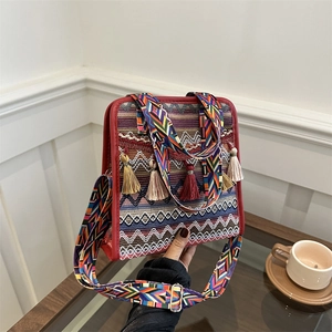Detail of bohemian shoulder bag with ethnic embroidery, colorful tassels and wide strap
