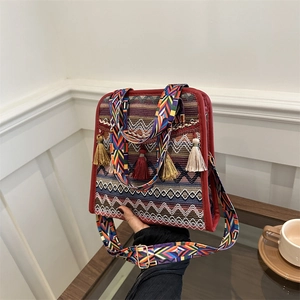Close-up of Bohemian woven shoulder bag with colorful tassels and red leather trim detail