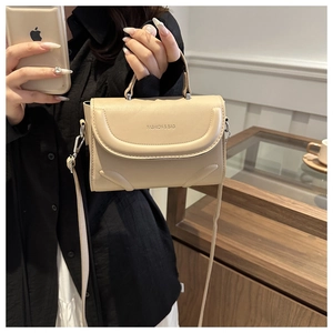 Detail of elegant beige crossbody bag with fashion text shown in a daily setting