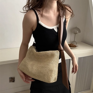 Minimalist straw woven tote bag with brown leather shoulder strap for summer vacation