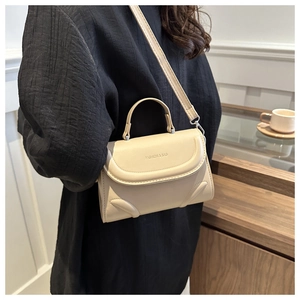 Detail view of the elegant beige square bag showing the textured leather and logo embossing
