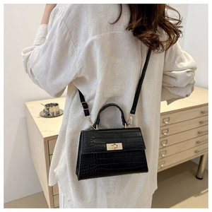 Detail of black crocodile pattern crossbody bag with golden clasp and adjustable strap