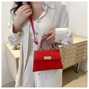 Detail of red crocodile texture handbag with gold clasp on beige linen outfit
