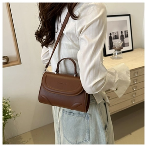 Detail of dark brown leather handbag with Fashion & Bag embossed logo and slim strap