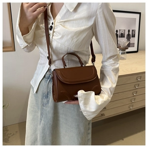 Detailansicht der braunen Crossbody-Tasche mit geprägtem XIN HOI-Schriftzug im Retro-Stil