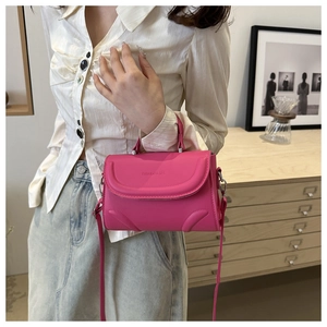 Detail of pink faux leather handbag showing fashion logo embossing and silver hardware