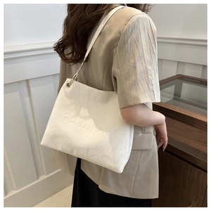 Close-up of elegant cream leather tote bag with embossed fashion text and gold hardware