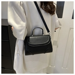 Detail of black leather handbag featuring FASHION & BAG embossing and quilted flap edges
