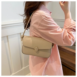 Détail du sac à bandoulière beige avec boucle ovale et sangle nouée sur mannequin