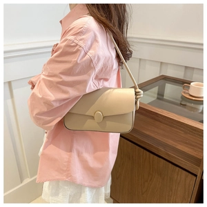 Détail d'un sac à bandoulière crème avec sangle nouée et boucle ovale élégante