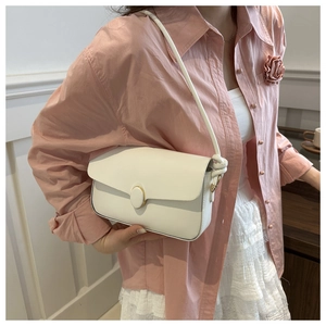 Détail du sac à bandoulière en cuir blanc avec fermoir doré et bandoulière nouée sur modèle