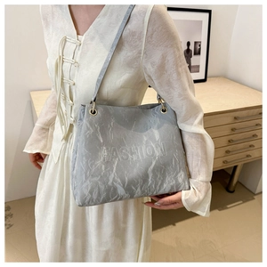 Macro detail of a light gray tote bag with pleated texture and FASHION embossed logo