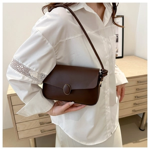 Détail du sac à bandoulière en cuir marron foncé avec boucle dorée et bandoulière nouée