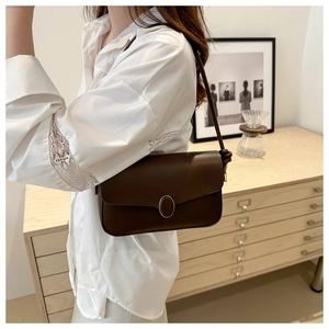 Détail du sac à bandoulière marron foncé en cuir avec boucle en métal ovale