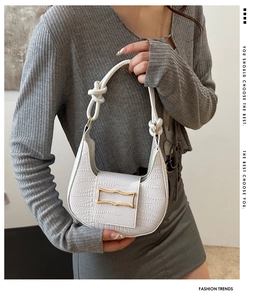 Detail of white half-moon bag with embossed texture, knot handle and gold buckle