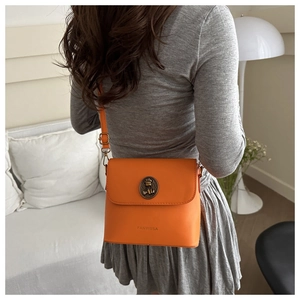 Mannequin portant un sac bandoulière orange vif avec un emblème d'ours vintage