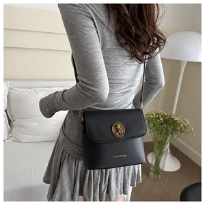 Detail of black crossbody bag with gold lion head buckle and adjustable strap