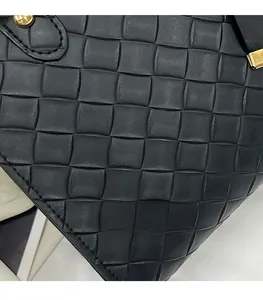 Détail du sac cabas en cuir tressé noir montrant le tissage artisanal et les clous dorés