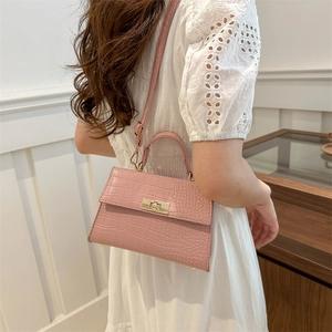 Pink crocodile pattern handbag with gold clasp shown on a model in a white lace dress