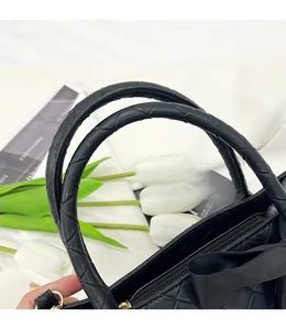 Détail de la poignée du sac fourre-tout noir avec texture tressée en losange et fermeture éclair