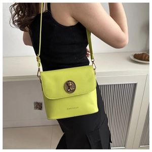 Détail du sac bandoulière vert néon avec emblème métallique vintage et bandoulière en cuir souple