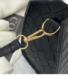 Détail du crochet en métal doré amovible sur un sac cabas en cuir tressé noir