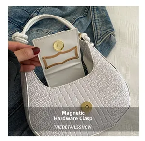 Close-up of white crocodile pattern baguette bag with magnetic clasp and knot handle