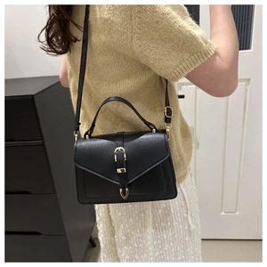 Detailed view of black vintage crossbody bag with gold buckle on a side-profile model