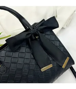 Détail du sac cabas tissé noir avec un grand nœud en satin et boucle en métal doré