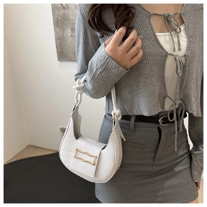 Detail of white embossed leather hobo bag with gold geometric buckle and braided handle