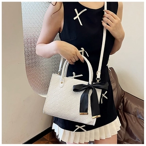Détail du sac cabas blanc tissé avec un grand nœud en satin noir et bandoulière chic