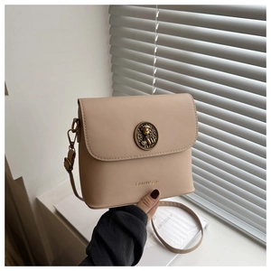 Vue détaillée de la boucle en métal ours rétro sur le sac à bandoulière beige minimaliste