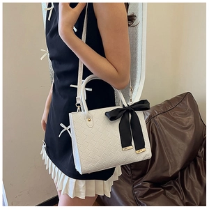Vue détaillée du sac cabas blanc tissé avec un nœud en satin noir et des garnitures dorées