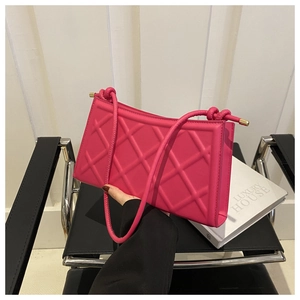 Detailed close-up of fuchsia quilted handbag with diamond pattern and gold metal hardware