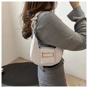 White crocodile pattern baguette bag with gold buckle shown on shoulder for profile view