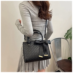 Détail du sac cabas tressé noir avec grand nœud et bordures métalliques dorées