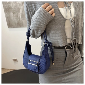 Detail of navy blue baguette bag with crocodile texture and gold buckle on shoulder