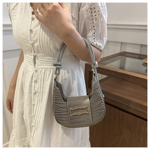 Detail of grey crocodile pattern hobo bag with gold buckle on shoulder strap
