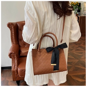 Détail d'un sac cabas tissé marron orné d'un grand nœud en satin noir élégant