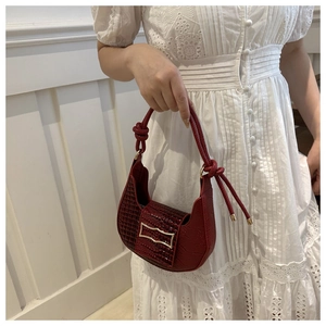 Detail of dark red crocodile pattern leather on the crescent shoulder bag with gold buckle