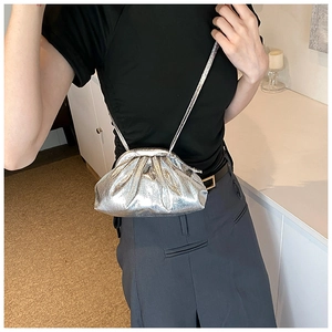 Gros plan du sac plissé argenté métallisé avec fine bandoulière porté par un mannequin