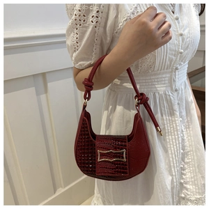 Close-up of burgundy croc-effect leather hobo bag with gold buckle and knotted strap