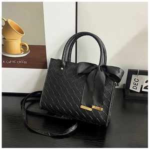 Détail du sac cabas tissé noir avec un grand nœud en satin et des finitions dorées
