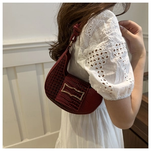Close-up of dark red baguette bag with crocodile texture and gold geometric buckle