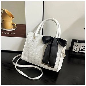 Détail du sac cabas tissé blanc avec nœud en soie noir et poignées rondes en décor chic
