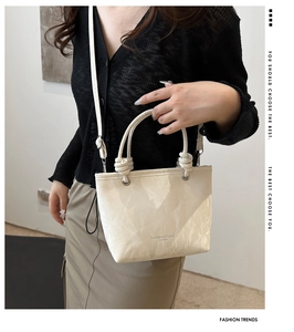 Detail of beige tote bag with marble texture, knot decor and slim shoulder strap