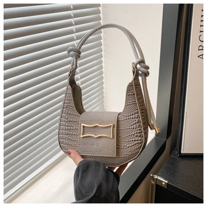 Detail of grey crocodile pattern bag with golden buckle and knotted handle design