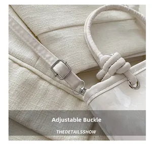 Detail of adjustable strap and silver metal buckle on a cream textured handbag