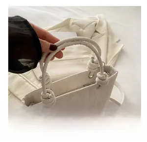 Detail of white knotted handle handbag with pleated texture and adjustable strap